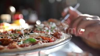 一个男人的手拿着一片热气腾腾的美味海鲜披萨，披萨上有山柑和橄榄